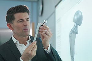Medical product designer inspecting hip joint model with graphical screen