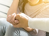 closeup of two people holding hands sitting on a bench